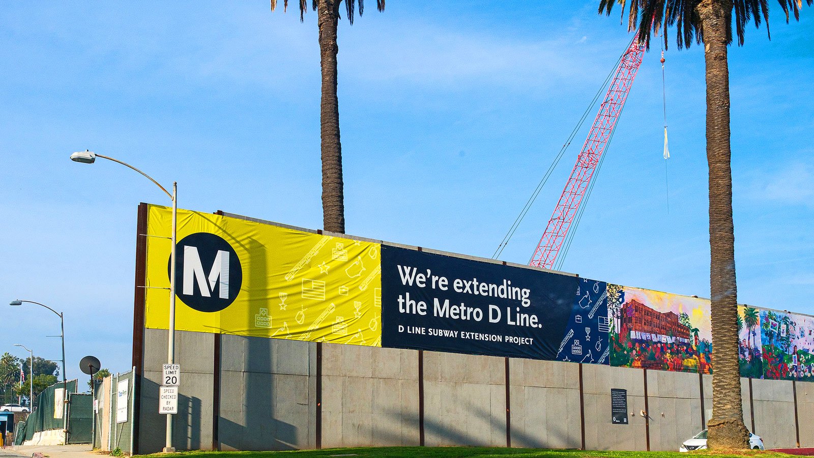 Construction crane behind a Metro D Line banner at the site of a future station in Westwood.