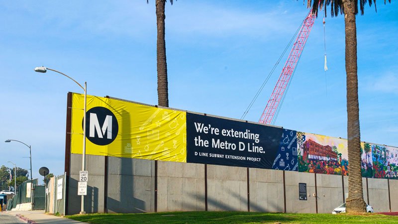 Construction crane behind a Metro D Line banner at the site of a future station in Westwood.