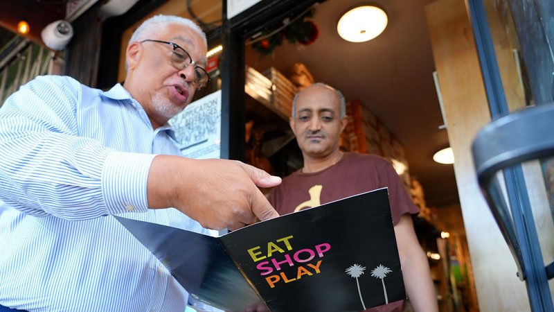 A restaurant owner looks on as a member of the Metro Eat Shop Play Outreach explains the program.