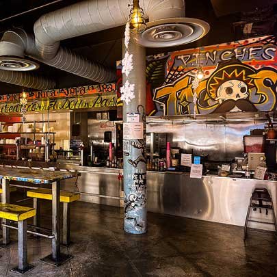 The festive, graffiti-cover decorations around the bar at Pinches Tacos.