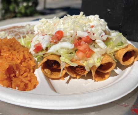 A delicious taquitos plate, covered in sour cream, cheese, tomatoes from Tacos Mexico.