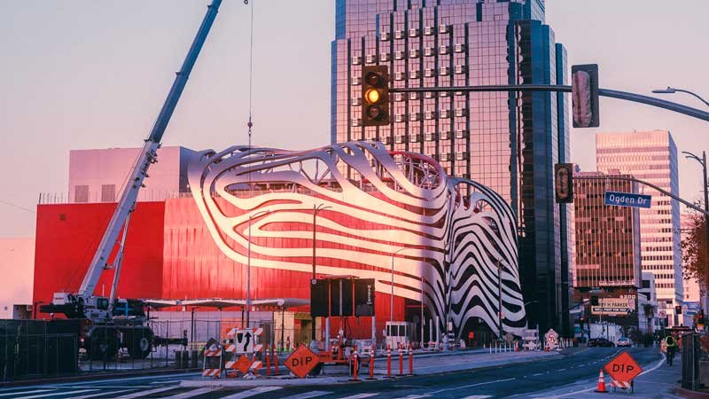 Construction along Wilshire Blvd at dusk with a crane and detour signs at street level.