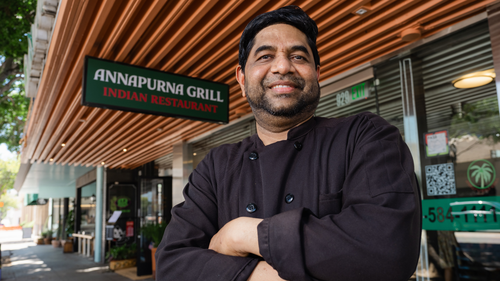 Annapurna Grill – chef standing outside the restaurant beneath the Annapurna Grill Indian Restaurant awning.