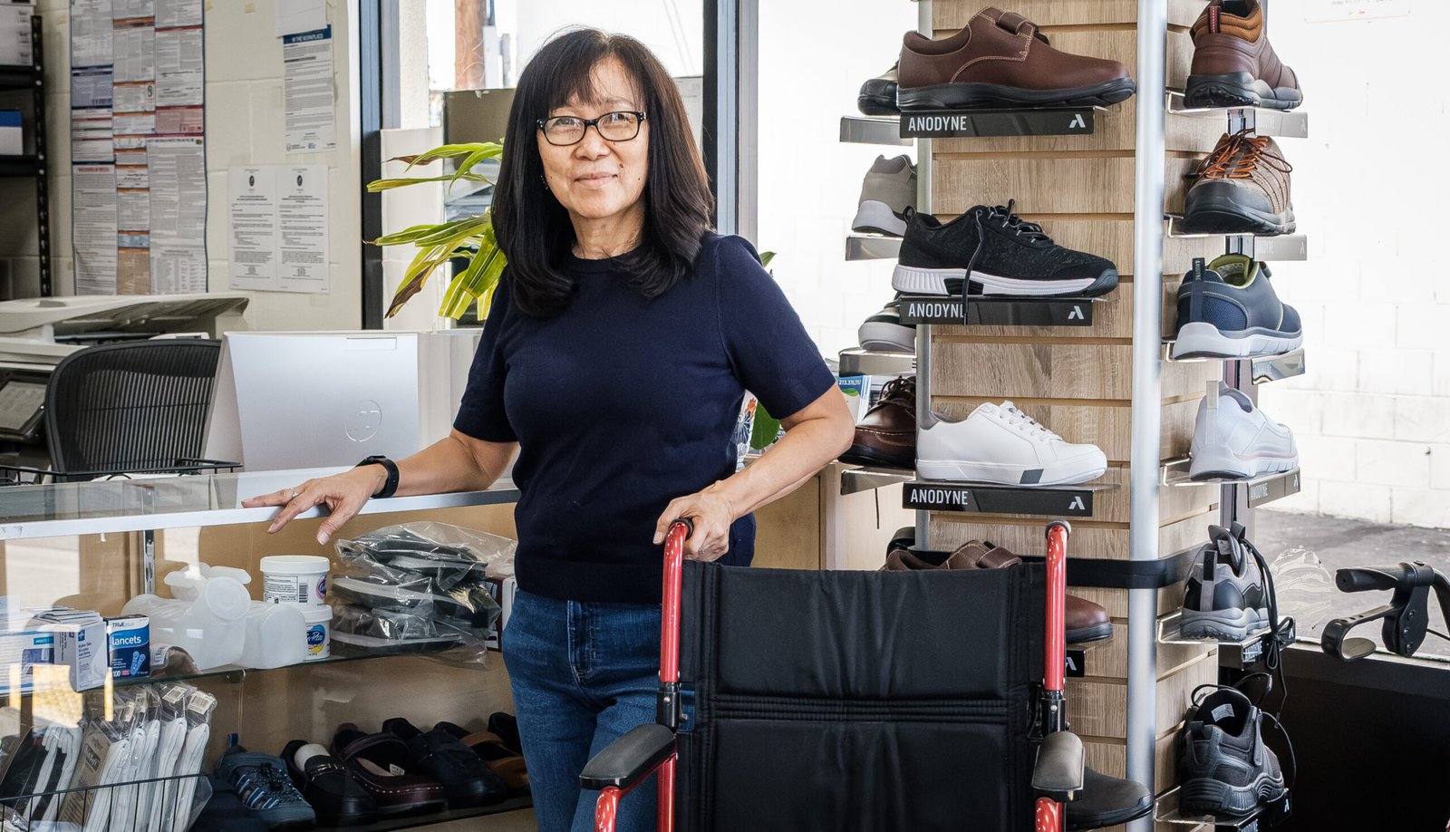 Care Concepts Inc. – staff member with a wheelchair beside displays of walkers, orthopedic shoes and mobility equipment.