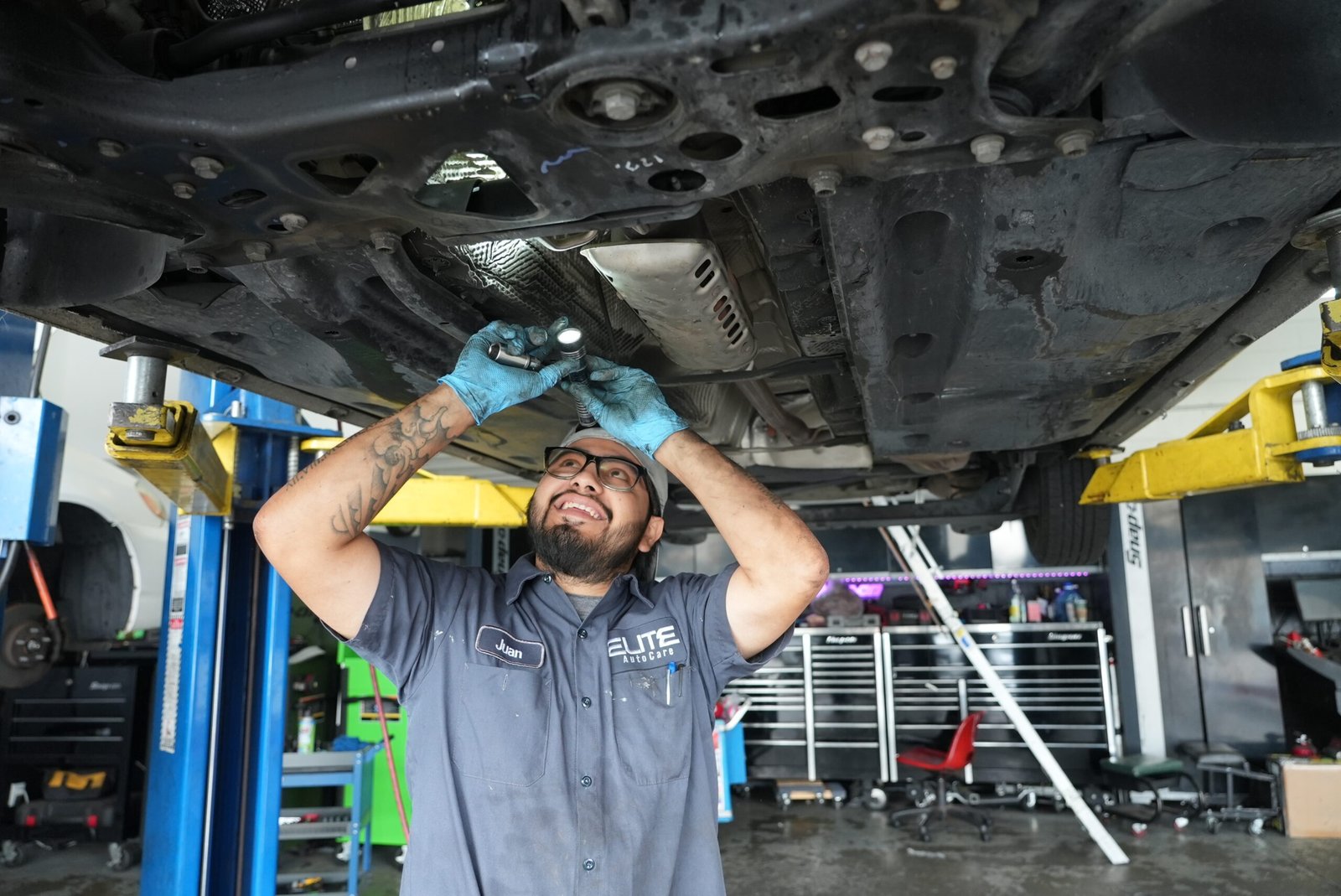 Elite Auto Care – mechanic working underneath a car raised on the lift in the service bay.