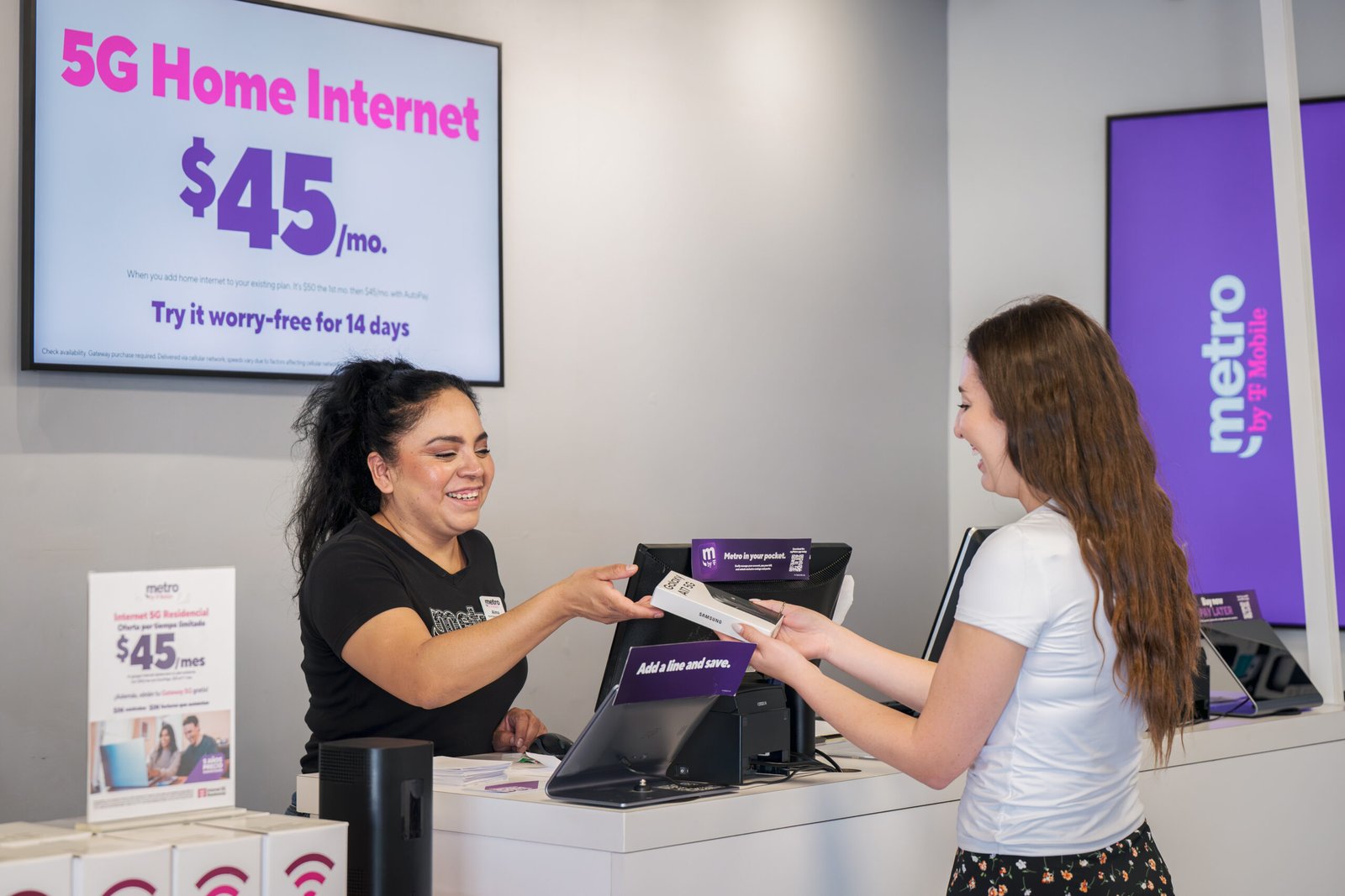 Metro by T-Mobile – store associate handing paperwork to a customer beneath a 5G Home Internet $45 per month sign.