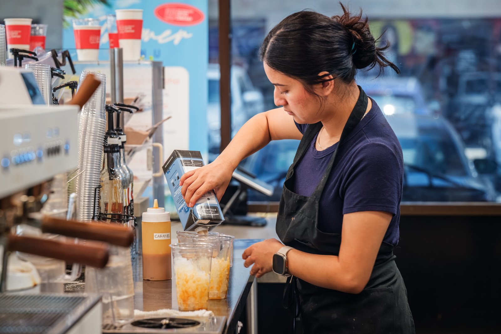 San Fernando Coffee Company – barista pouring an iced coffee behind the espresso bar.