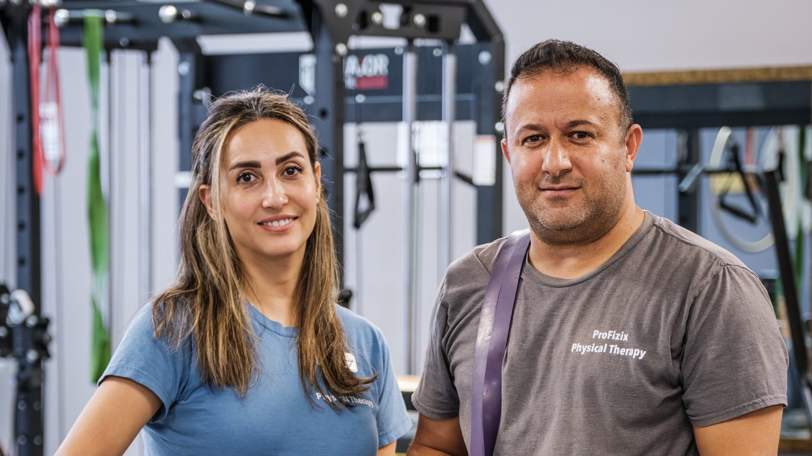ProFizix Physical Therapy & Wellness – two physical therapists standing together among the exercise equipment in the treatment gym.